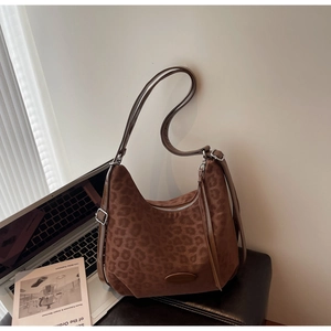 Detail of leopard print shoulder bag with suede texture and silver zipper on a desk