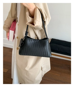 Detail of a black woven leather tote bag with Intrecciato pattern and side knot tie
