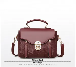 Detail of wine red crossbody bag showing snake pattern texture and gold metal clasp
