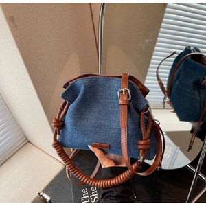 Detail of blue denim bucket bag with brown leather strap and spiral handle textured finish