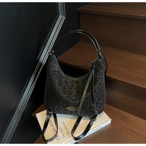 Detail of dark leopard print tote bag with metallic logo on a wooden staircase