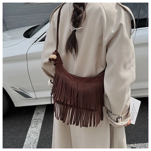 Close-up of brown suede tassel shoulder bag with wooden beads and bohemian fringe detail