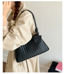Detail of black woven leather tote bag showing intricate cross-stitch texture and strap