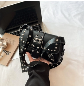 Detail of punk style black baguette bag with silver rivets and wide adjustable strap