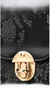 Detail of black snake embossed texture and vintage gold oval clasp on the bag