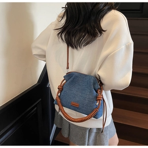 Close-up of retro blue denim shoulder bag with spiral brown leather handle details