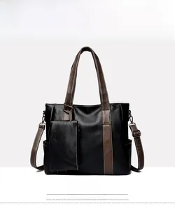 Detail view of black and brown tote bag with smooth leather texture and hanging pouch
