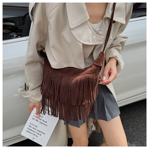 Detailed texture of dark brown suede fringe on a retro-style bohemian shoulder bag