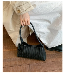 Close-up of black woven shoulder bag showing fine texture and sturdy handles