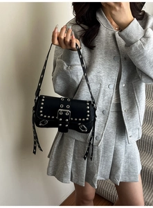 Detail of black punk shoulder bag with silver rivets and metallic buckle strap