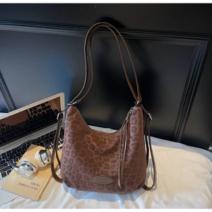 Detail of leopard print hobo shoulder bag with brown leather strap in a workspace setting