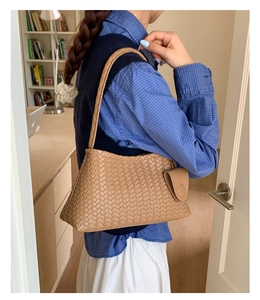 Detail of woven leather shoulder bag in tan with matching coin purse on a female model