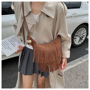 Detail of bohemian brown suede crescent bag featuring long tassels and wooden beads