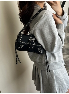Detail of black punk underarm bag with silver studs and buckle strap on a model