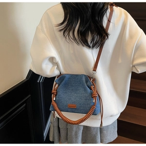 Deep blue denim dumpling bag with brown leather rope handle shown on a model