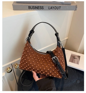 Close-up of brown suede handbag with pearl beads, black leather handle and silver hardware