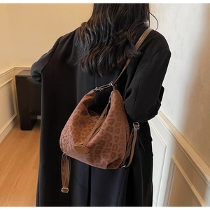 Detailed back view of a woman wearing the leopard print suede hobo bag over a black coat