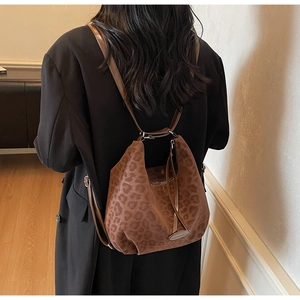 Detailed back view of a stylish leopard print backpack on a model in a warm room