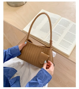 Detailed close-up of brown woven texture and stylish side buckle on the shoulder bag
