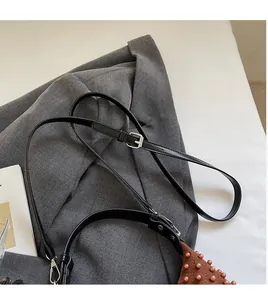 Close-up of brown quilted bag with beaded accents and adjustable black shoulder strap