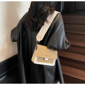 Detail of khaki and cream contrast bag with wide fabric strap and fashion logo