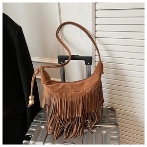 Detailed macro view of a vintage brown suede hobo bag with fringe and wooden bead charms