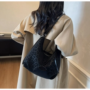 Detail view of black leopard print hobo bag worn over a beige trench coat