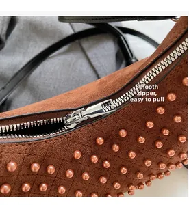 Detail of smooth silver zipper and rose gold studs on brown suede punk shoulder bag