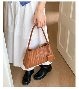 Detail of brown woven leather texture on a crescent handbag with heart charm