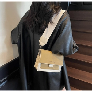 Borsa a tracolla in pelle bicolore alla moda con cinturino largo sulla spalla della modella