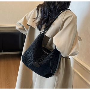Detail of grey leopard print hobo bag with adjustable black strap on khaki trench coat