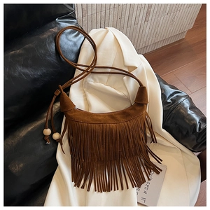 Detailed macro view of the brown suede fringe and decorative wooden beads on a crossbody bag