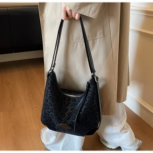 Close-up of leopard print hobo bag with adjustable strap on a model wearing a trench coat