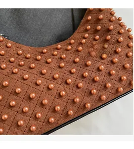 Close-up of quilted brown suede shoulder bag with bronze beaded accents and luxury stitching