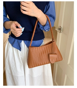 Detailed view of caramel brown woven leather texture on a stylish shoulder baguette bag