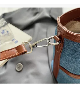 Close-up of bright silver swivel hardware on blue denim and brown leather bucket bag