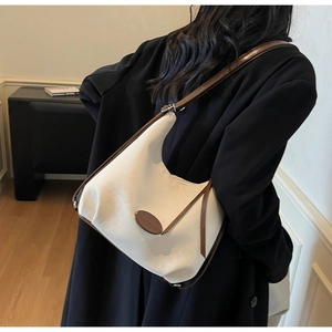 Detail of minimalist cream shoulder bag with brown trim shown from a back perspective