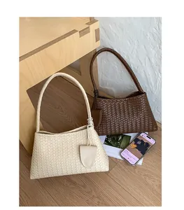 Detail view of woven leather shoulder bags in cream and dark brown with triangle charms