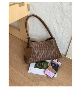 Close-up of brown woven leather shoulder bag with matching mini pouch and smooth texture
