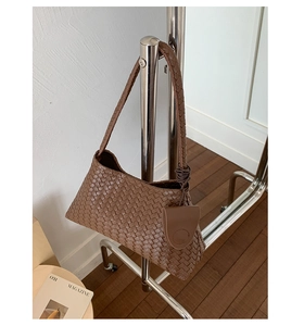 Detail of dark brown woven leather texture on tote bag hanging on metal rack