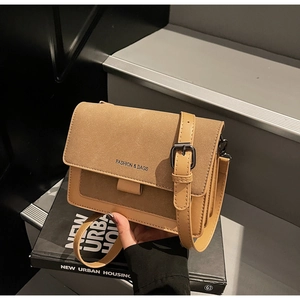 Dettaglio della borsa a tracolla marrone chiaro con texture scamosciata e logo fashion