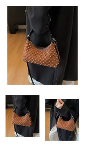 Detail of a punk-style brown beaded shoulder bag with textured studs and black handle