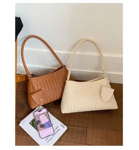 Detailed view of woven crescent shoulder bags in brown and beige with small charm pouches