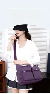 Detailed view of purple nylon crossbody bag with multiple zip pockets and quilted stitching