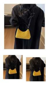 Detailed view of yellow suede pearl shoulder bag with black handle and silver metal hardware