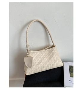 Detail of beige woven hobo shoulder bag with a matching mini pouch on a black chair