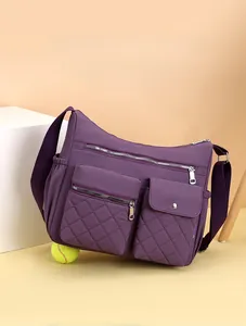 Detail view of large capacity purple nylon crossbody bag with multi-zipper compartments