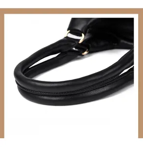 Détail de la poignée en cuir noir d'un sac à main avec anneaux dorés et surpiqûres précises