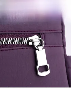 Close-up of smooth silver metal zipper on durable purple nylon shoulder bag fabric