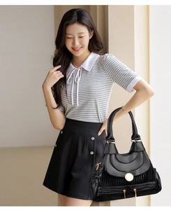 Détail d'un sac noir plissé avec boucle dorée et fermeture éclair latérale pratique